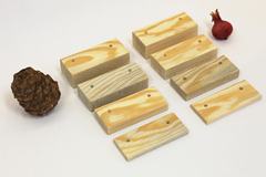 Set di 8 tacche in pino con i fori per le viti, accanto a una pigna